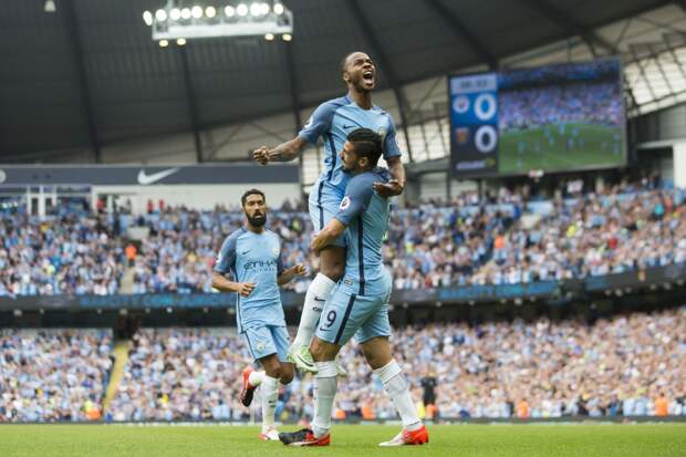 Manchester City's English midfielder Raheem Sterling (up) is held aloft by teammate