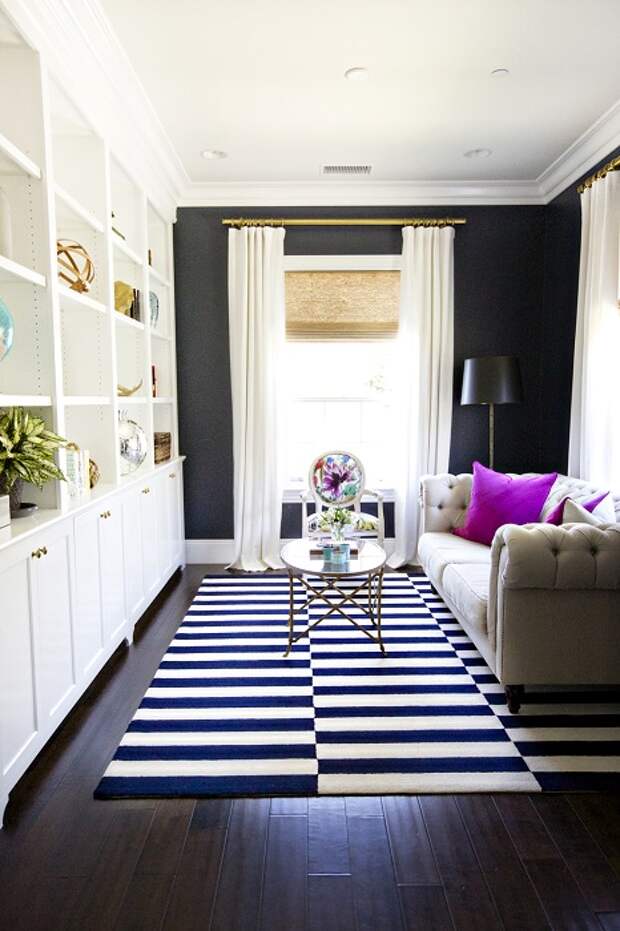 Хороший вариант расширить пространство гостиной с использованием полосатого черно-белого ковра.