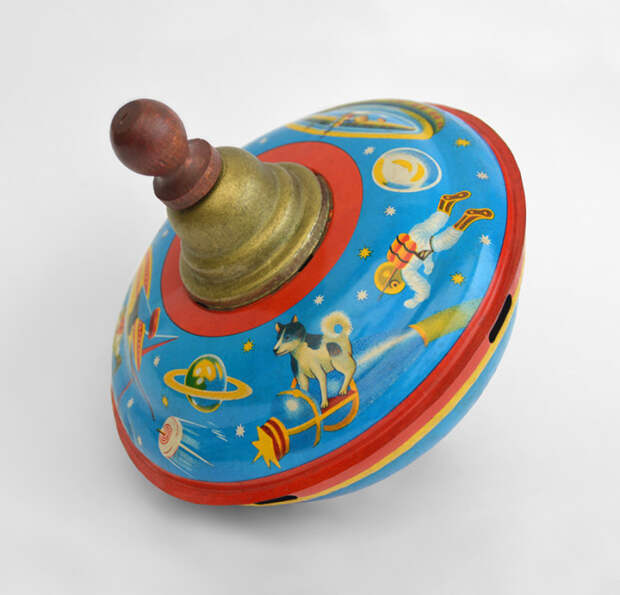 Волчок японской фирмы S. I. Toys, 1958 год. Собака Лайка стоит на «ракете», отдаленно похожей на космический аппарат «Спутник-2».