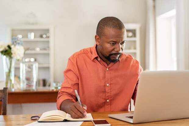 A person at a laptop taking notes.