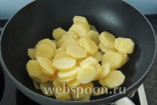 Тем временем нарезаем картофель пластинками толщиной около 3 мм и кладём в горячее масло — 1 ст.л.