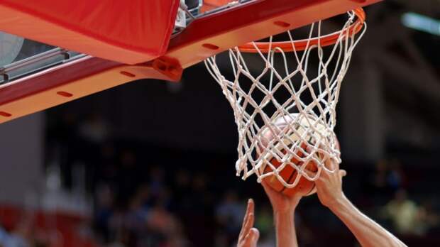 A basketball player grabs a rebound over an opponent.