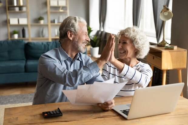 A retired couple high-fiving after reducing taxes on RMDs.