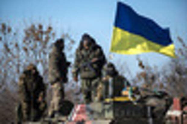 Ukrainian soldiers stand next to a Ukrainian national flag atop an armored vehicle
