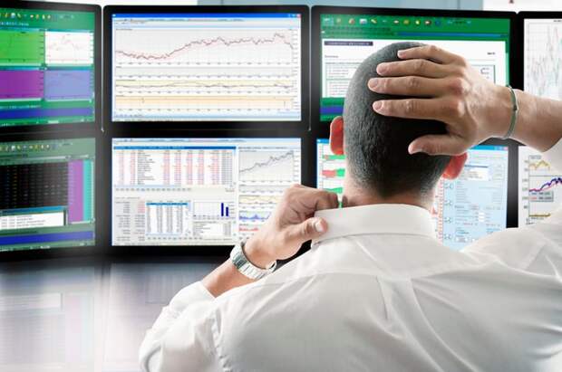 Person looking at several computer monitors displaying charts and data.