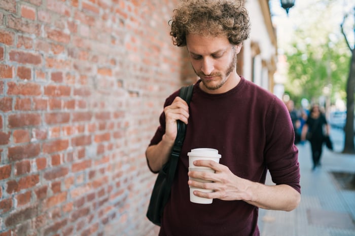 A person holding a to-go cup outside.
