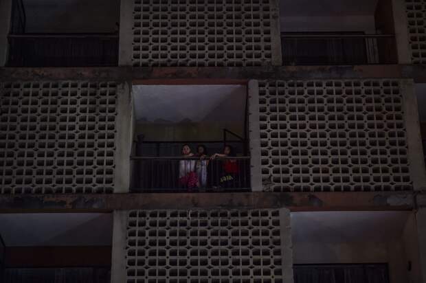 Женщины выходят из обесточенного многоквартирного дома в Каракасе 7 марта 2019 года.png