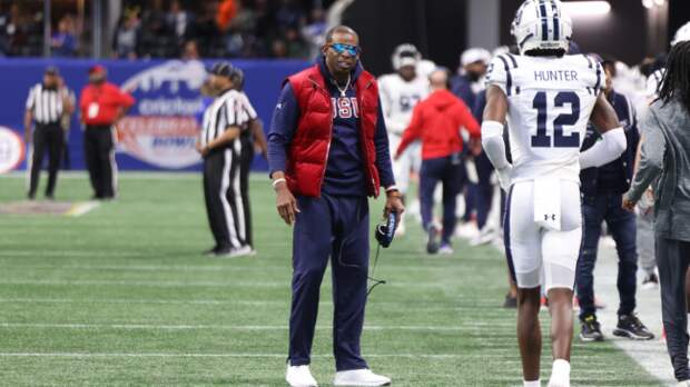 Deion Sanders and Travis Hunter talk on the sidelines.