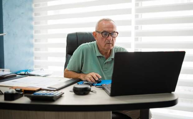 A person sitting at a desk and using a laptop.