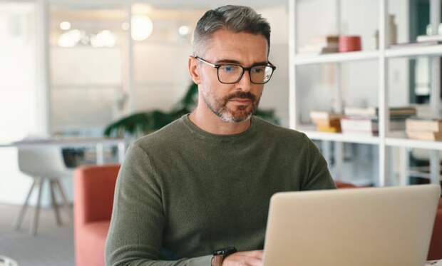 A person with a serious expression at a laptop.