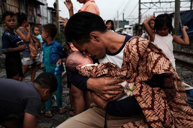 10. Джонатан держит на руках свою дочь после возвращения с работы бедность, джакарта, железная дорога, индонезия, нищета, репортаж, трущобы