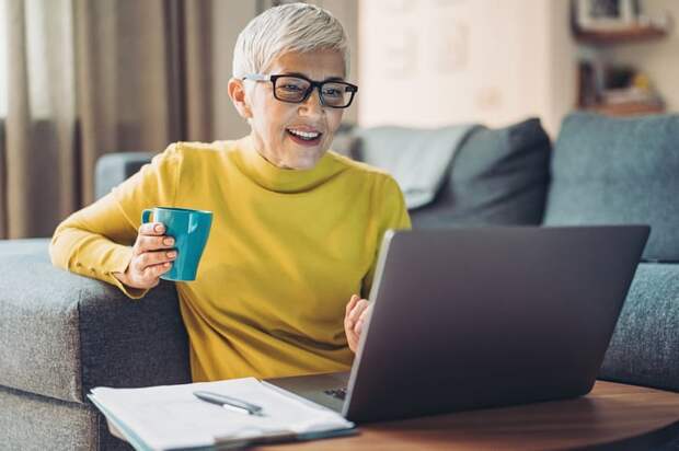 A smiling person at a laptop.