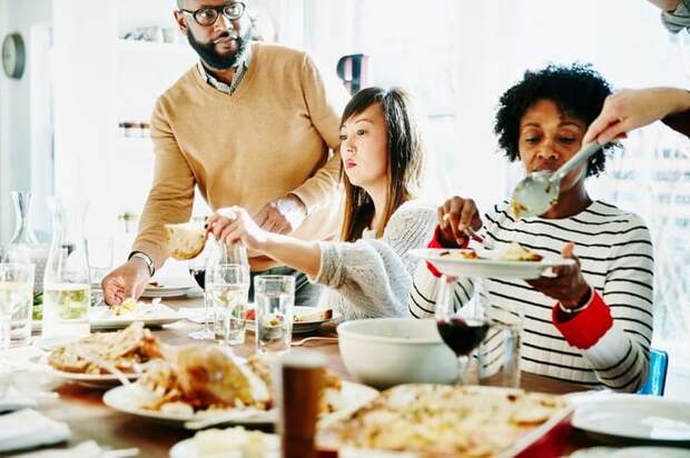 Friends and family serve each other food during a holiday meal.