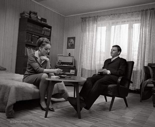 Молодые москвичи курят в просторной комнате с образцовым советским интерьером. 1966