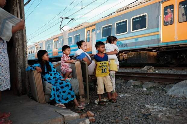 22. Семья наблюдает за проходящим мимо их дома поездом бедность, джакарта, железная дорога, индонезия, нищета, репортаж, трущобы