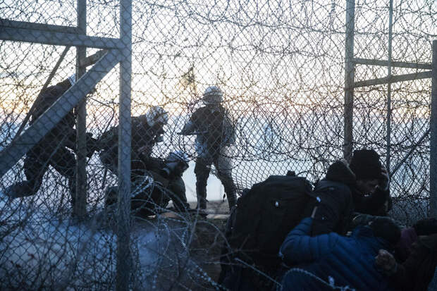 Греческие пограничники против мигрантов, пытающихся пересечь границу через отверстия в заборе