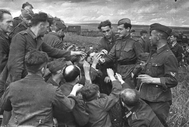 Советский солдат делится сигаретами с немецкими военнопленными, 1943 год.