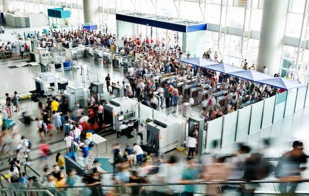 A busy airport security entrance with lots of people rushing through.