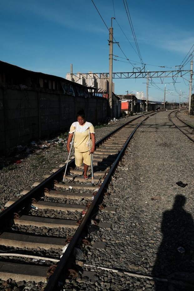 13. Женщина с одной ноги идет на костылях прямо по шпалам бедность, джакарта, железная дорога, индонезия, нищета, репортаж, трущобы