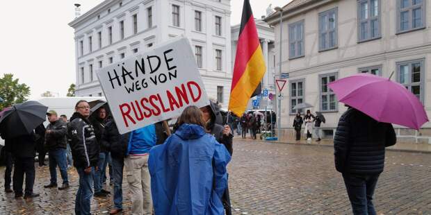 Участница акции против политики в отношении России с плакатом Руки прочь от России на одной из улиц Шверина.