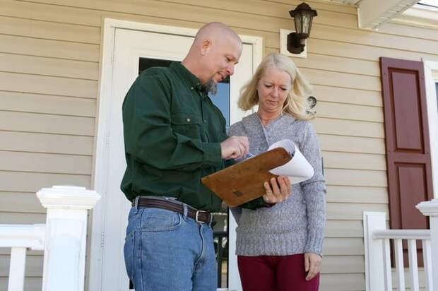 Woman on porch talking to man with clipboard.