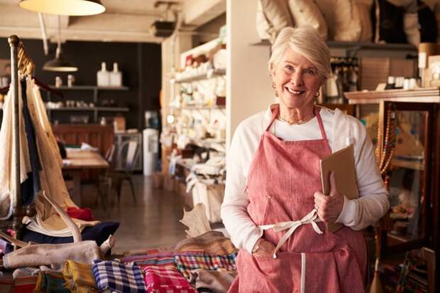 A person in an apron standing in front of a row of fabrics.
