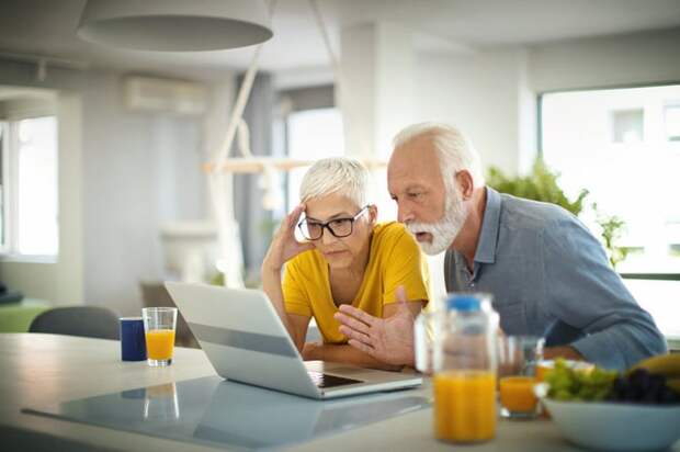 Two people with stunned expressions looking at a laptop.