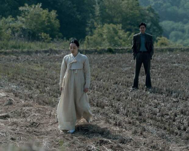 Sunja in white dress and Koh in barren field