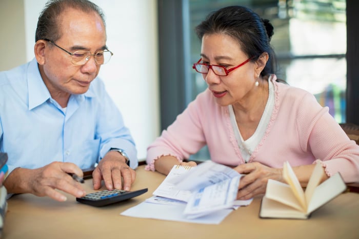 Two people looking at a calculator and documents.