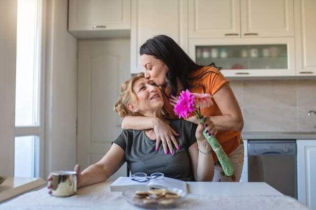 Daughter gives flowers and a hug to mother
