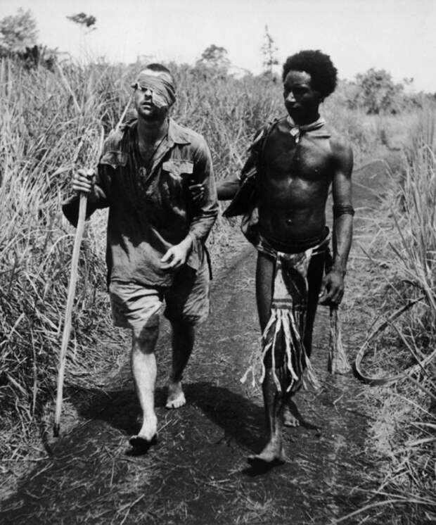 Уроженец Папуа-Новой Гвинеи, сопровождает раненого австралийского солдата, 1942 год.
