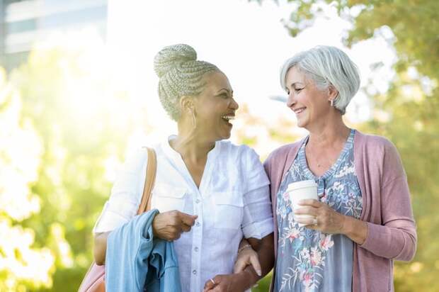Two people smiling at each other outside.