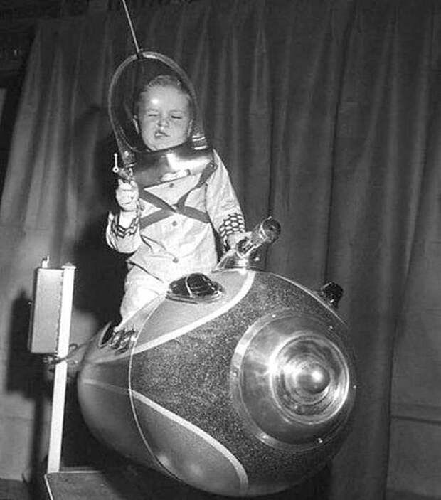 Космический рейнджер. Ребенок играл на космическом корабле, управляемом монеткой, на Американской ярмарке игрушек в 1953 году. история, черно-белая фотография, юмор