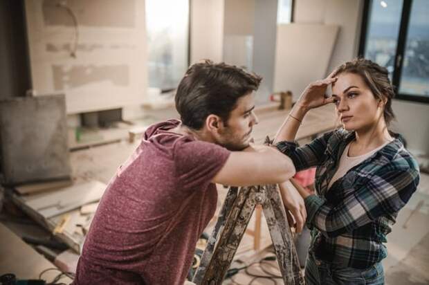 A stressed-looking couple pausing work on renovating their living room.