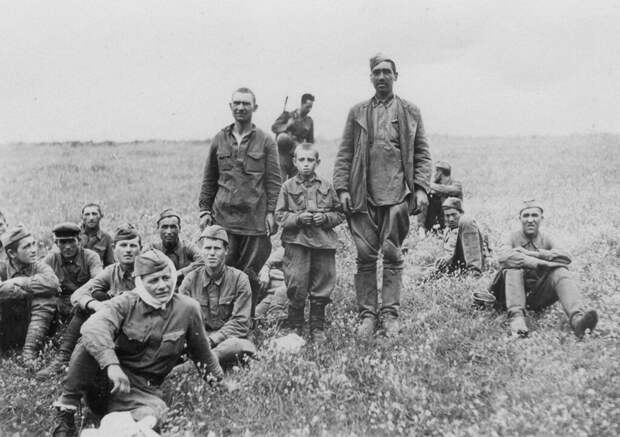 Группа пленных красноармейцев с воспитанником. На заднем плане немецкий конвоир. 1942 г.