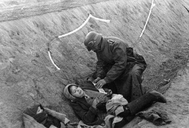 Немецкий солдат наносит повязку раненной русской женщине.