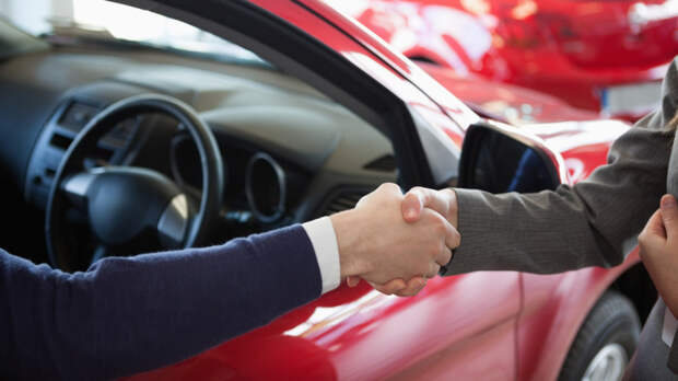 Close up of a man shaking hand to a woman in a dealership