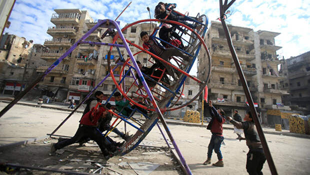Дети качаются на качелях в разрушенном Алеппо, Сирия