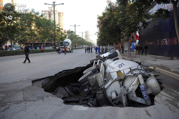Китай. Сиань, Шэньси. 28 сентября 2012 года. Автобетоносмеситель, завалившийся на бок в карстовую воронку. (REUTERS/China Daily)