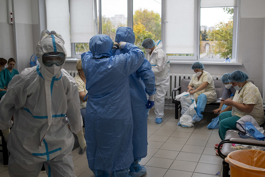 Спецкор «Новой газеты» Елена Костюченко провела более суток в «красной зоне» одного из самых больших перепрофилированных под лечение covid госпиталей – больнице № 15 в Москве. Она узнала, как проходит лечение больных и как себя чувствуют врачи в медучреждении, которое уже семь месяцев без перерыва работает с коронавирусом. «Тромбы у всех. D-димер, который показывает склонность организма к тромбообразованию, — в норме 1–2, 500 максимум, у наших 1000, 3000, 7000! — говорит хирург Виктор Аносов. — Тромб в голову — инсульт, в сердце — инфаркт, в лёгких — легочная эмболия. С конечностями проще. Ампутации идут каждый день». 15-я больница, Москва. 1474 пациента, 225 поступило за сутки. Вся больница, за исключением «синего» и диагностического корпусов, — красная зона. В синем корпусе лежат люди, чей коронавирус пока не подтвержден. В диагностическом заседает штаб и спят врачи между сменами. Рядом с больницей построены еще три быстровозводимых блока для выздоравливающих. Весной было четыре, но один разобрали, на его месте сейчас строят скоропомощной корпус — для экстренных. Есть роддом, где лежат роженицы с коронавирусом.