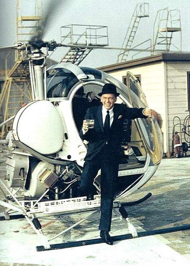 Фрэнк Синатра сходит с вертолета с напитком в руке. 1964