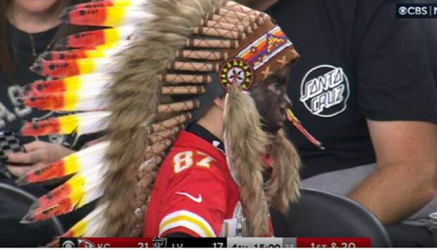 kid wearing a headdress and face paint at Chiefs game