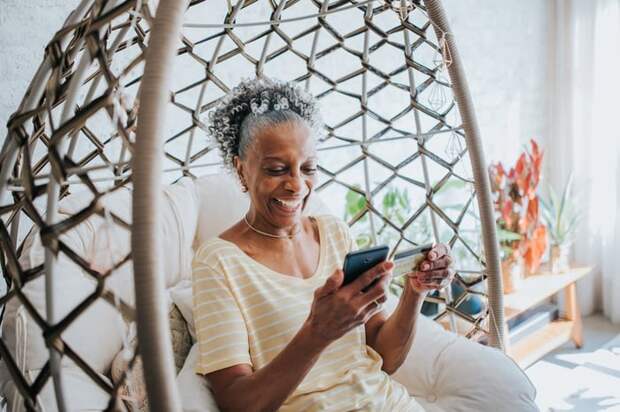 Senior woman holding a credit card and her cell phone smiling.