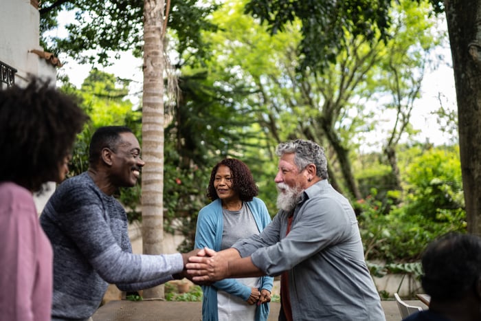 Group of smiling friends meeting up and shaking hands.