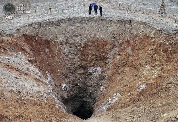 Китай. Гуанъюань, Сычуань. 28 февраля 2013 года. Местные жители осматривают новообразованную карстовую воронку. (REUTERS/Stringer)