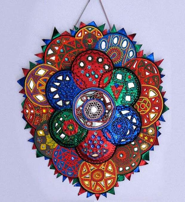 Настенное панно можно сделать, украсив диски яркой тканью, обвязав их или обклеив цветной плёнкой