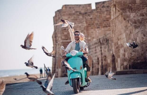 Tourists riding a motorized scooter through an old European town.