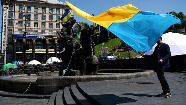 Молодой человек с украинским флагом у памятника основателям Киева на площади Независимости. Архивное фото