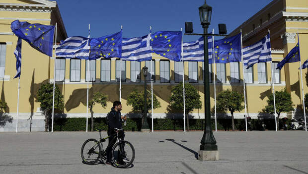 Мужчина с велосипедом на фоне флагов Греции и Евросоюза. Архивное фото