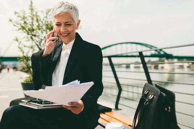 A businessperson holding documents and talking on a phone.